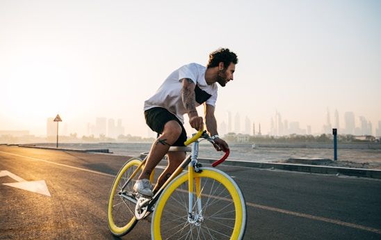 man on bicycle riding on the side of a beach 